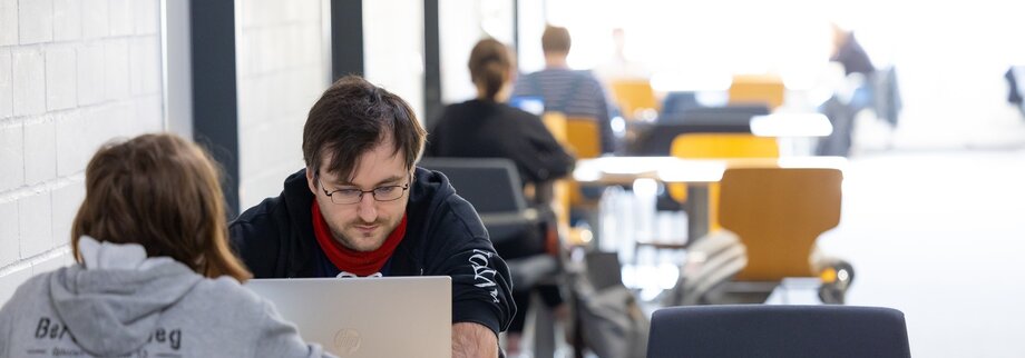 Mehrere Studierende sitzen an einem Tisch und arbeiten.