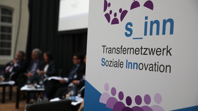 Aufsteller des Transfernetzwerk Soziale Innovation bei einer Podiumsdiskussion.