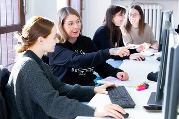 Mehrere Studentinnen sitzen in Partnerarbeit vor Bildschirmen.