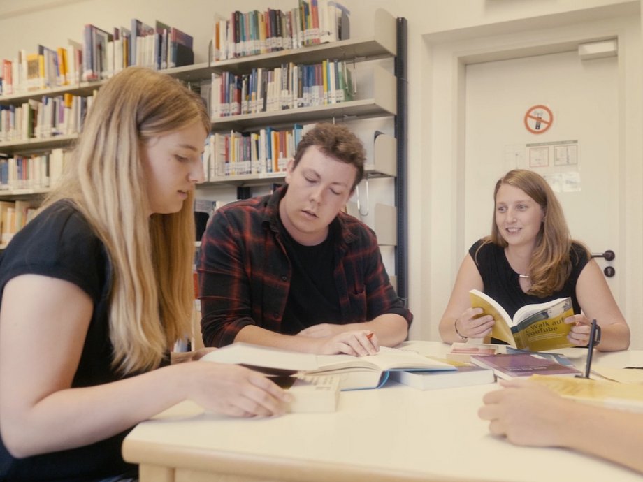 Eine Gruppe Studierender lernt gemeinsam in einer Bibliothek.