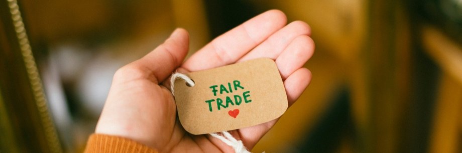 Hand hält ein Etikett, auf dem Fair Trade geschrieben steht.