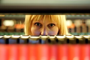 Studentin blickt durch Bücherregal

