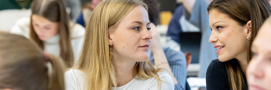 Mehrere Studierende sitzen im Hörsaal und hören aufmerksam zu.


